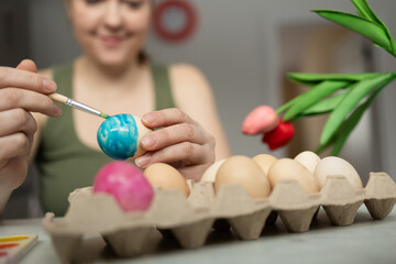 A joyful person painting colorful Easter eggs at home, celebrating creativity and the arrival of spring