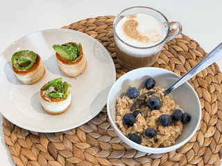 Delicious breakfast with coffee, blueberry oatmeal, and savory pastries on a woven mat