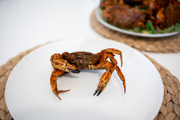 Cooked crab on white plate with prepared seafood in background
