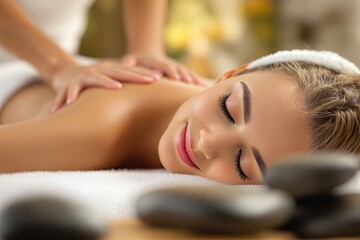 Obraz premium Woman enjoying relaxing massage in spa with soft focus stones in the foreground.