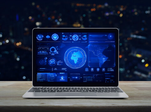 Laptop computer with digital world map with data charts and stats screen on wooden table over blur colourful night light office city tower and skyscraper, Futuristic user interface technology online
