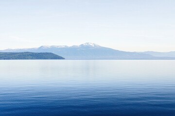 Fototapeta premium Mountain Lake Gradient: A mountain lake with water transitioning from clear near the shore to deep blue in the center.
