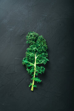 Green kale leaf on dark background, top view with copy space. Healthy detox vegetables . Clean eating and dieting concept. Top view with copy space. Health kale benefits