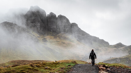 Woman with backpack hiking on a foggy path to the Old Man of Storr on the Isle of Skye, Scotland, UK