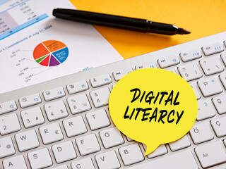 Digital literacy sticky note on keyboard with charts and pen promoting online education