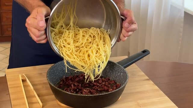 Chef in kitchen mixing ingredients for spaghetti carbonara