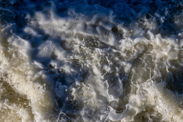 Rough flow of foaming water in the river, close-up, background