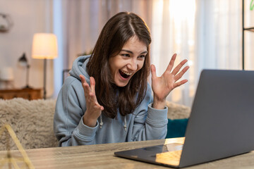 Happy young Caucasian woman browsing online store on laptop suddenly exclaims Wow after finding...