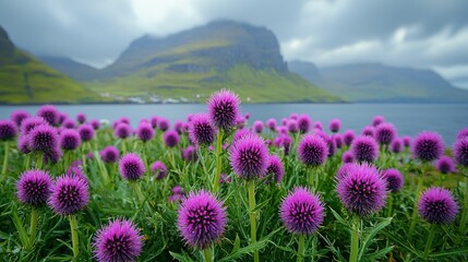 Obraz premium Purple flowers blooming near the serene lake with mountains in the background. A scenic view of nature's beauty.