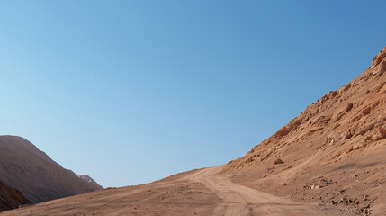 Naklejka premium Desert Road Through Arid Landscape: Dirt Road Between Rocky Hills Under Blue Sky