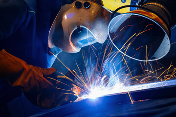 Industrial welding process, Factory weld worker in workplace, dark light with blue sparks