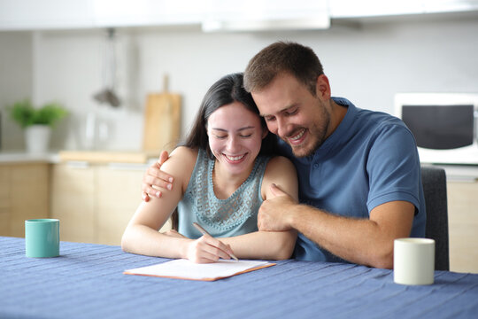 Happy interracial couple signing paper contract at home