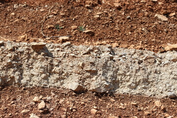 Brown and cream-colored sediment layers along a roadside on the mountain slopes