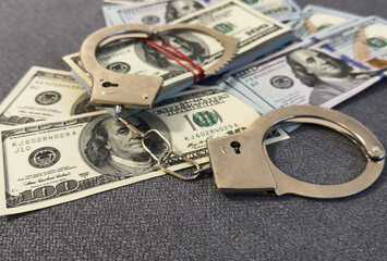 American dollars and handcuffs, Concept of ideas of corruption, dirty money or financial crimes.
