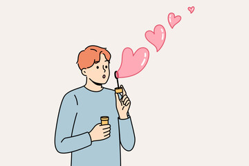 Romantic man uses heart-shaped soap bubbles to show love and kindness to people around him. Concept of romantic mood and desire to enter into serious relationship or marry girl you like