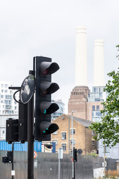 This image showcases traffic lights in the foreground with a historically significant power station rising prominently in the background, symbolizing progress and history in London UK