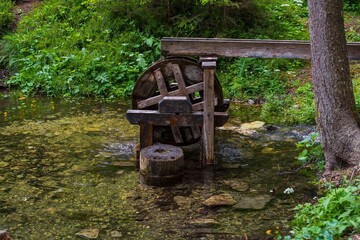 Naklejka premium Wooden mill on a lake in a mountain alpine forest. Scenery.