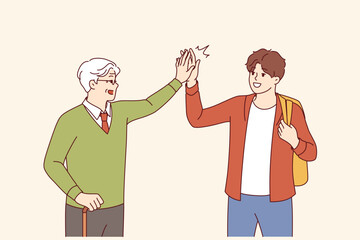Intergenerational friendship between teenager and old man high-fiving each other as sign of solidarity. Intergenerational friendship between gray-haired grandfather with crutch and grandson