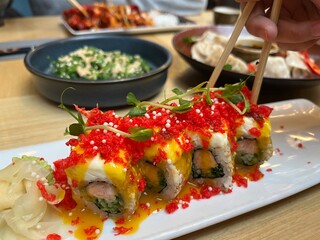 Japanese restaurant table with Red Dragon Sushi, seaweed salad, dumplings. Sushi with salmon, panko tiger prawns, cucumber, unagi sauce, mayonnaise, sesame seeds