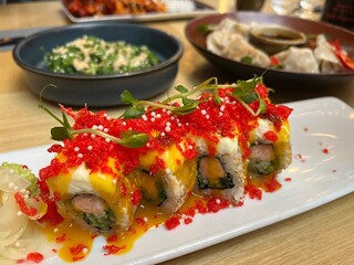 Japanese restaurant table with Red Dragon Sushi, seaweed salad, dumplings. Sushi with salmon, panko tiger prawns, cucumber, unagi sauce, mayonnaise, sesame seeds