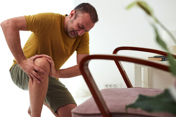 Man with painful knee and leg injury at home.