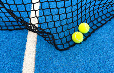 Yellow ball on floor behind paddle net in blue court outdoors. Padel tennis is a racquet game. Professional sport concept