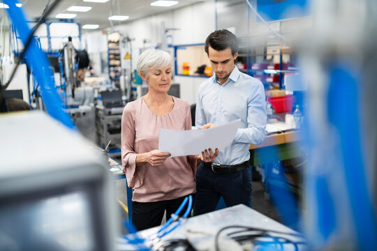 Businessman and senior woman looking at plan in a factory