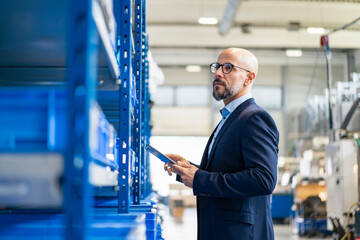 Businessman with tablet in factory storehouse