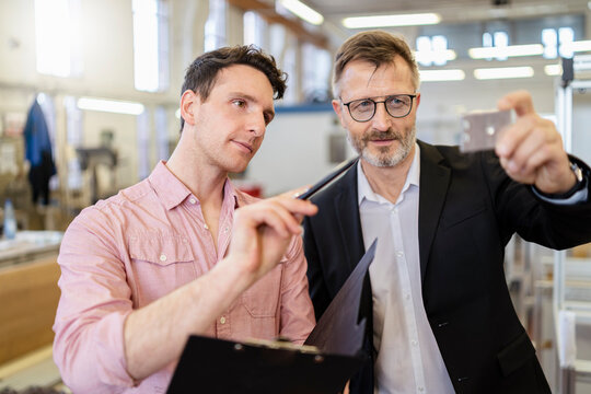 Two men in factory examining workpiece