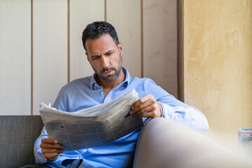 Businessman sitting down reading newspaper