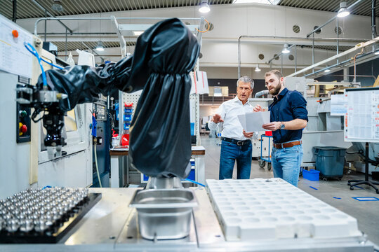 Businessman holding documents and discussing with co worker at factory