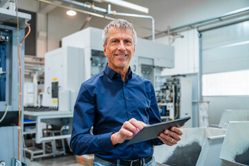 Smiling engineer using tablet PC at industry