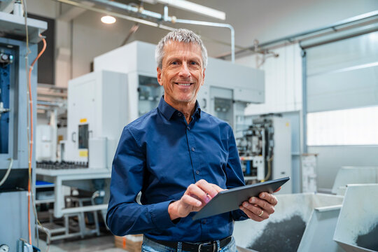 Smiling engineer using tablet PC at industry