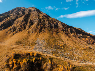 Rock mountain peaks autumn hills on blue sky and cloud background on sunny day, trekking view at Juta, Georgia. Brown and yellow colors of grass field on big mountain, beauty landscape.