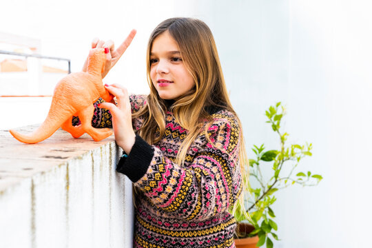 Girl playing with dinosaur toy at home