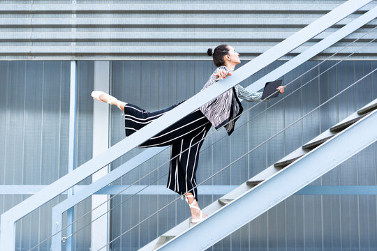 Female ballet dancer with smartphone and tablet standing on steps