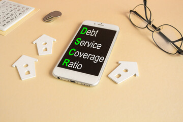 Concept words DSCR debt service coverage ratio on the mobile phone screen. Beautiful beige...