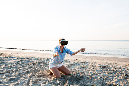 Thailand, woman using virtual reality glasses on the beach in the morning light