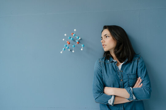 Female scientist studying molecule model, looking for solutions