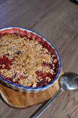 The dessert is freshly baked, with juicy, bubbling fruit filling visible beneath the crunchy crumble layer. Fruit crumble, homemade baking cake