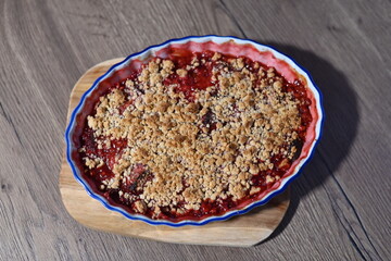 The dessert is freshly baked, with juicy, bubbling fruit filling visible beneath the crunchy crumble layer. Fruit crumble, homemade baking cake