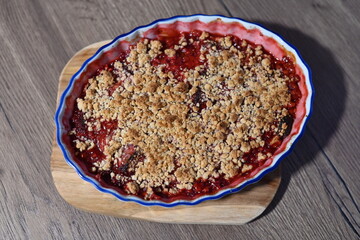 The dessert is freshly baked, with juicy, bubbling fruit filling visible beneath the crunchy crumble layer. Fruit crumble, homemade baking cake