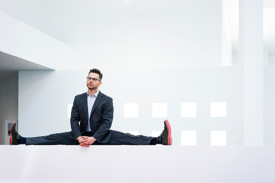 Businessman doing the splits on reception desk in office