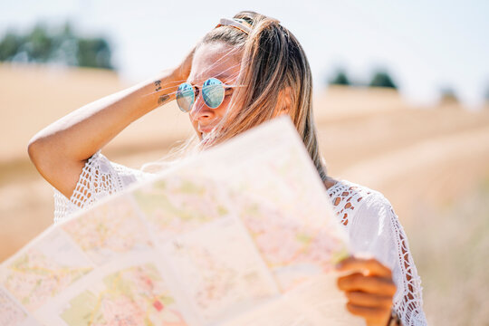 Blond young woman wearing mirrored sunglasses holding map looking at distance