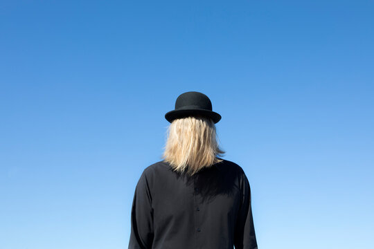 Blond hair covering man's face wearing bowler hat