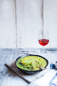 Bowl of Fresh green pea soup with spring onions and a glass of blush Wine