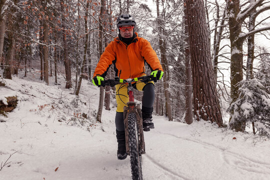 Man riding mountainbike on path in winter forest