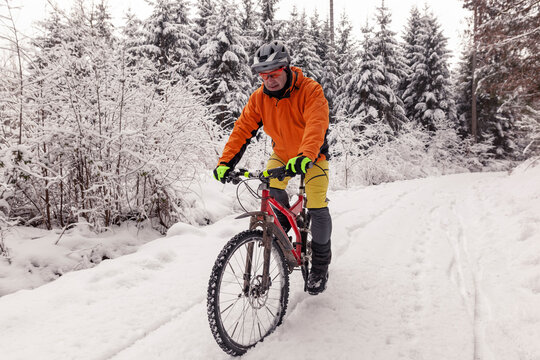 Man riding mountainbike on path in winter forest