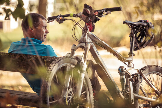 Man with mountainbike having a break sitting on a bench