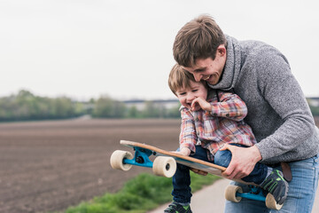 Father and son having fun, playing with skateboard outdoors